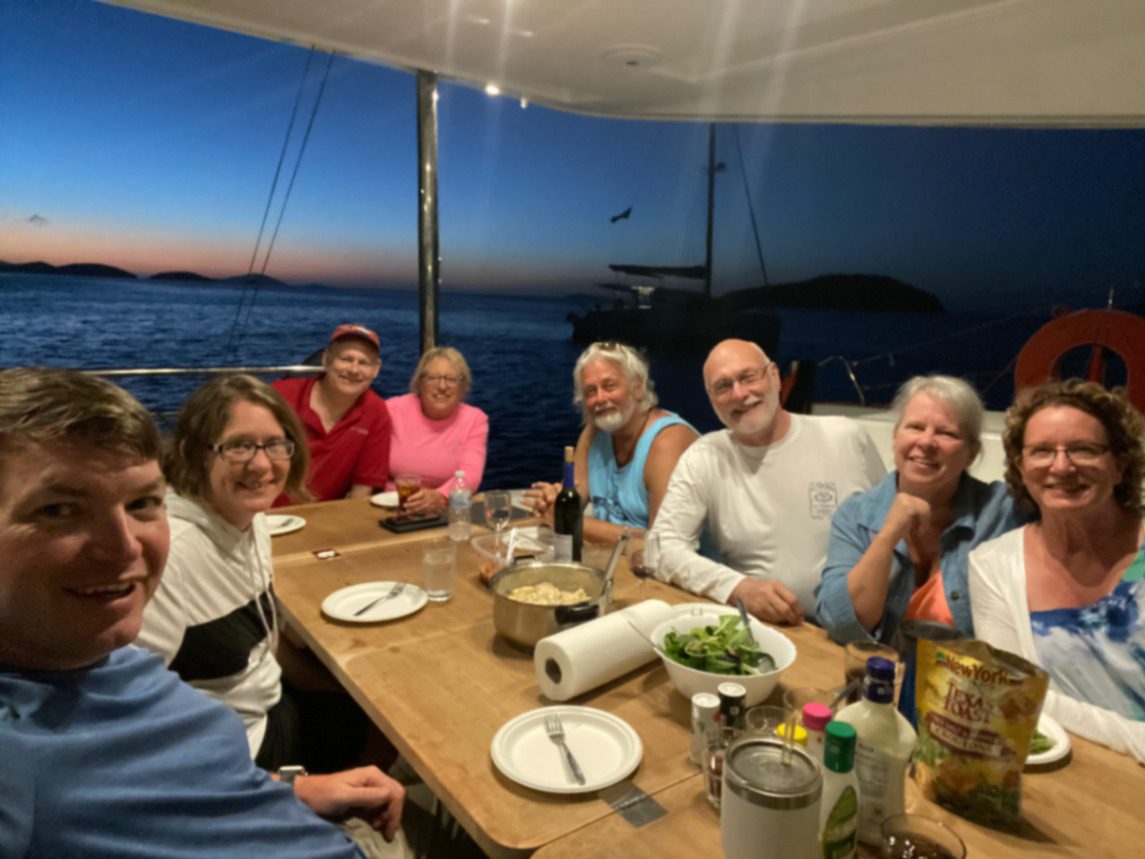 Friends sharing a sunset dinner aboard the catamaran