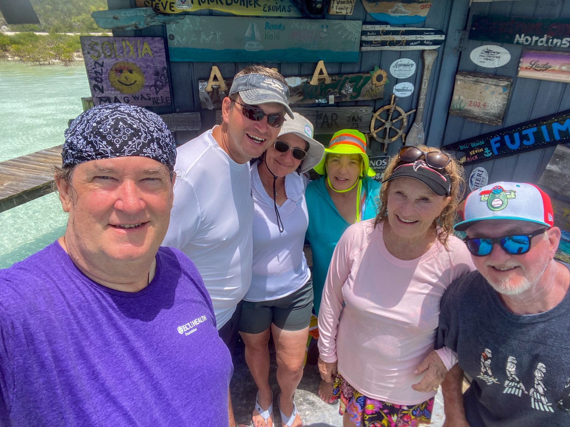 Guests posing at the famous boater's sign wall in the Exumas